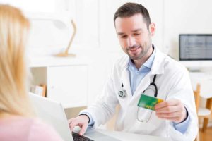 Woman paying for rehab and giving her insurance card to a doctor