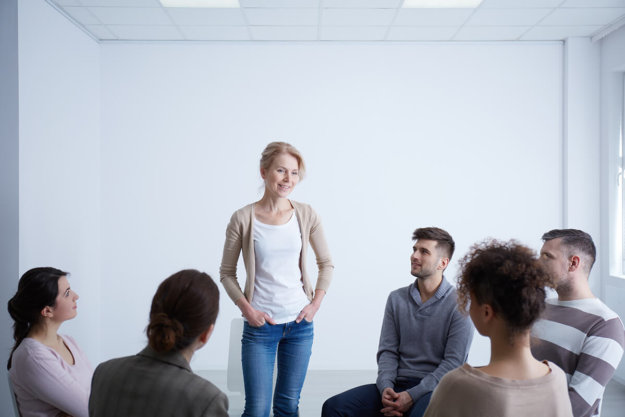 woman standing and talking during group therapy and learning about rehab insurance coverage